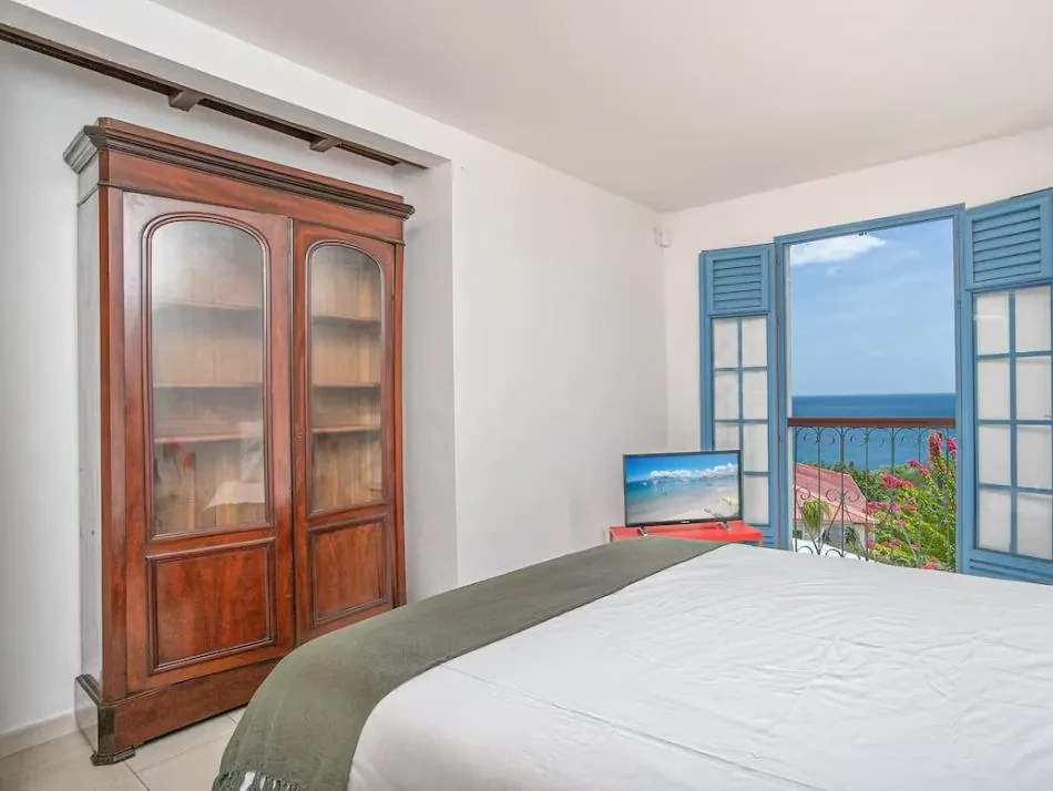 Chambre avec armoire ancienne et balcon ouvrant sur la mer