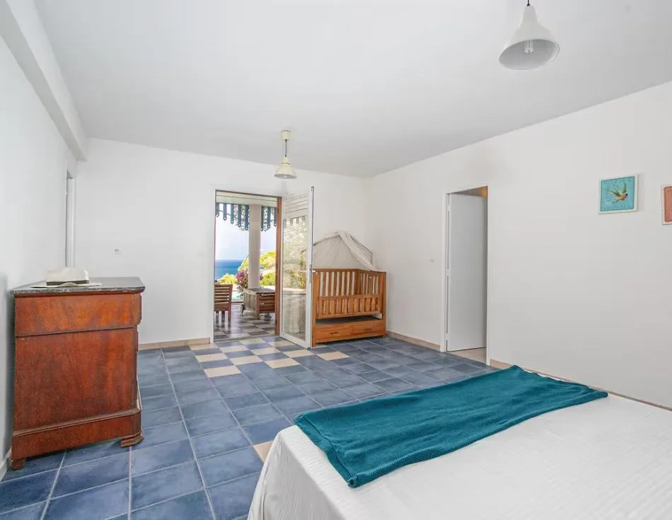 Chambre lumineuse avec lit bébé, ouvrant sur une terrasse