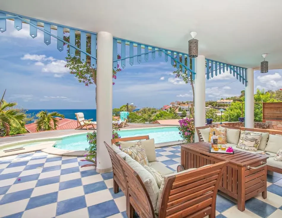 Salon extérieur couvert au bord de la piscine, sol en damier bleu et blanc